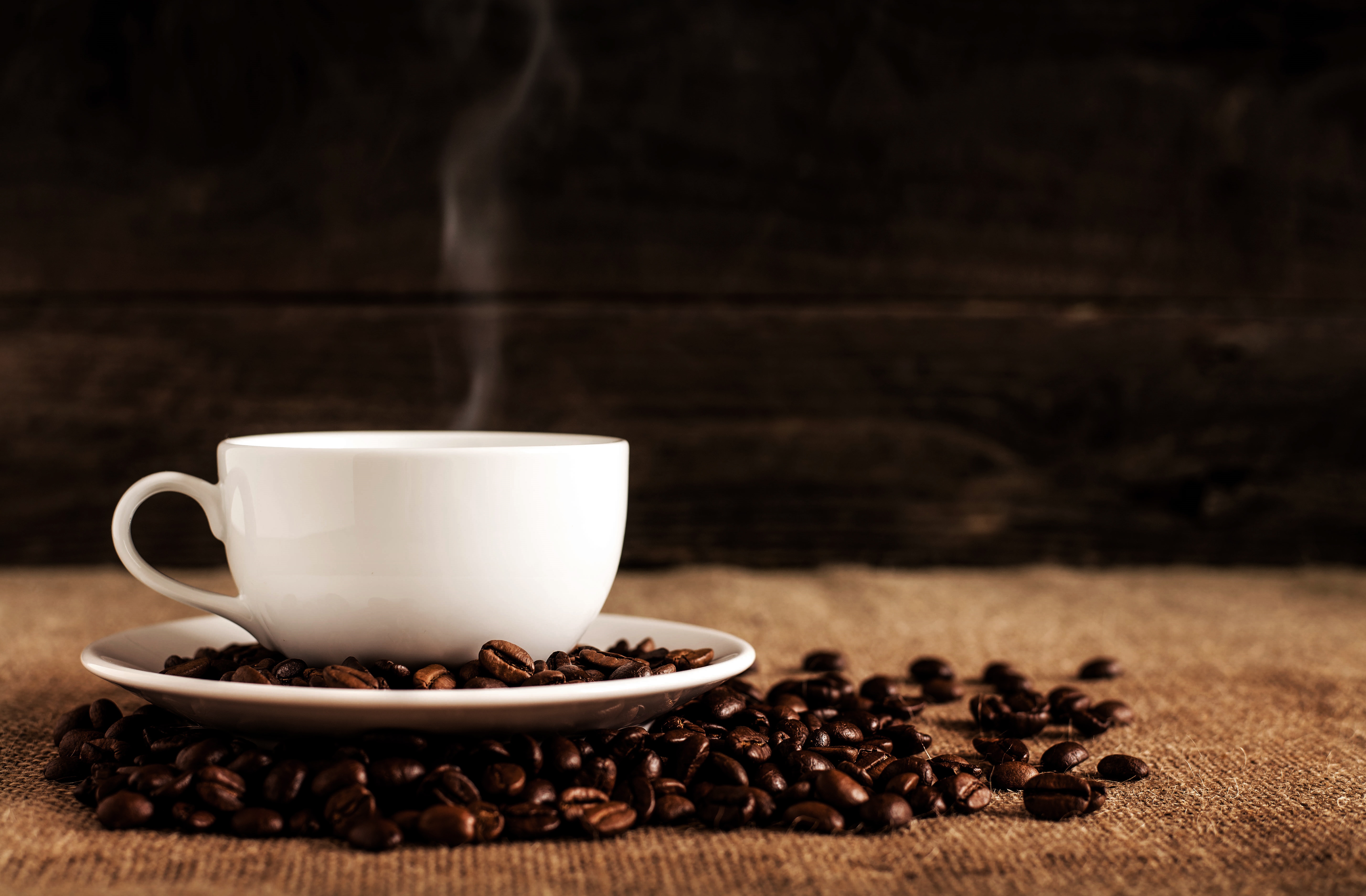 Coffee beans littered around white cup